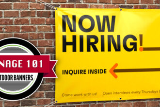 Two people smiling and hanging up a poster