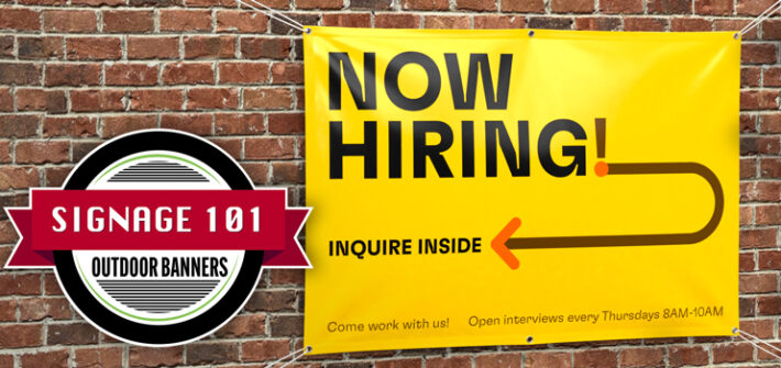 Two people smiling and hanging up a poster